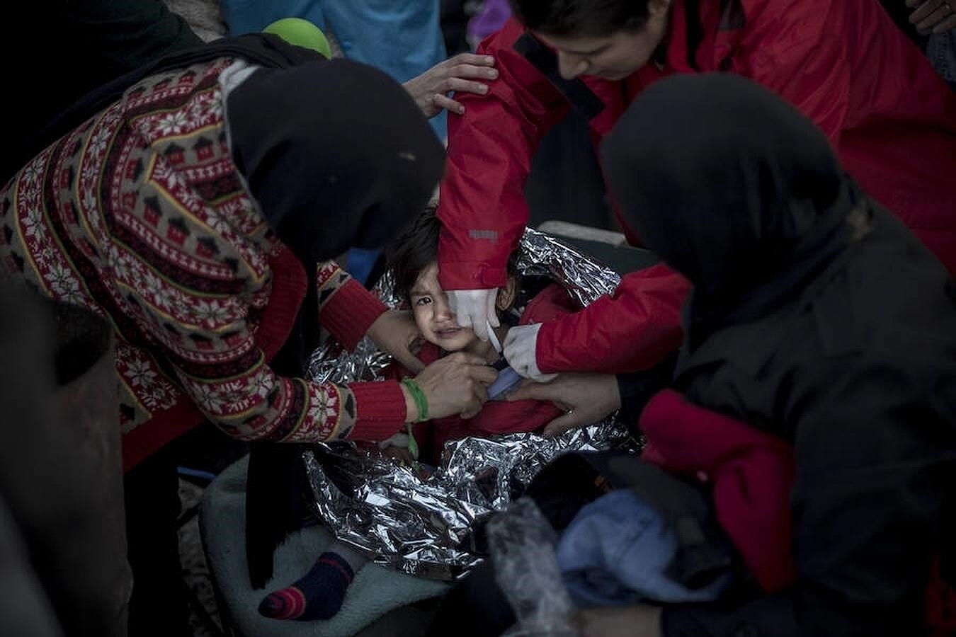 Un niña refugiada siria es atendida por su familia y una sanitario-voluntaria en el campamento de Platanos después de llegar desvanecida en la barca con la que ella, su familia y unas 40 personas más cruzaron el mar Egeo desde Turquía.