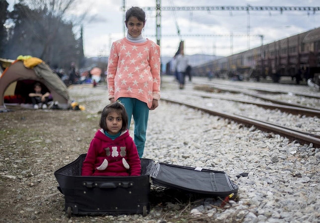 Unas niñas sirias juegan con una maleta en la estación de tren de Idomeni.