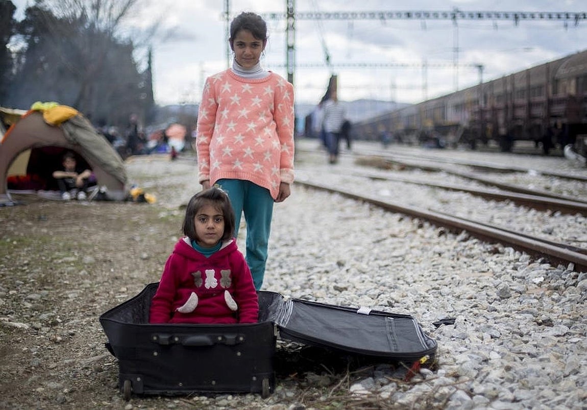 Unas niñas sirias juegan con una maleta en la estación de tren de Idomeni.. 