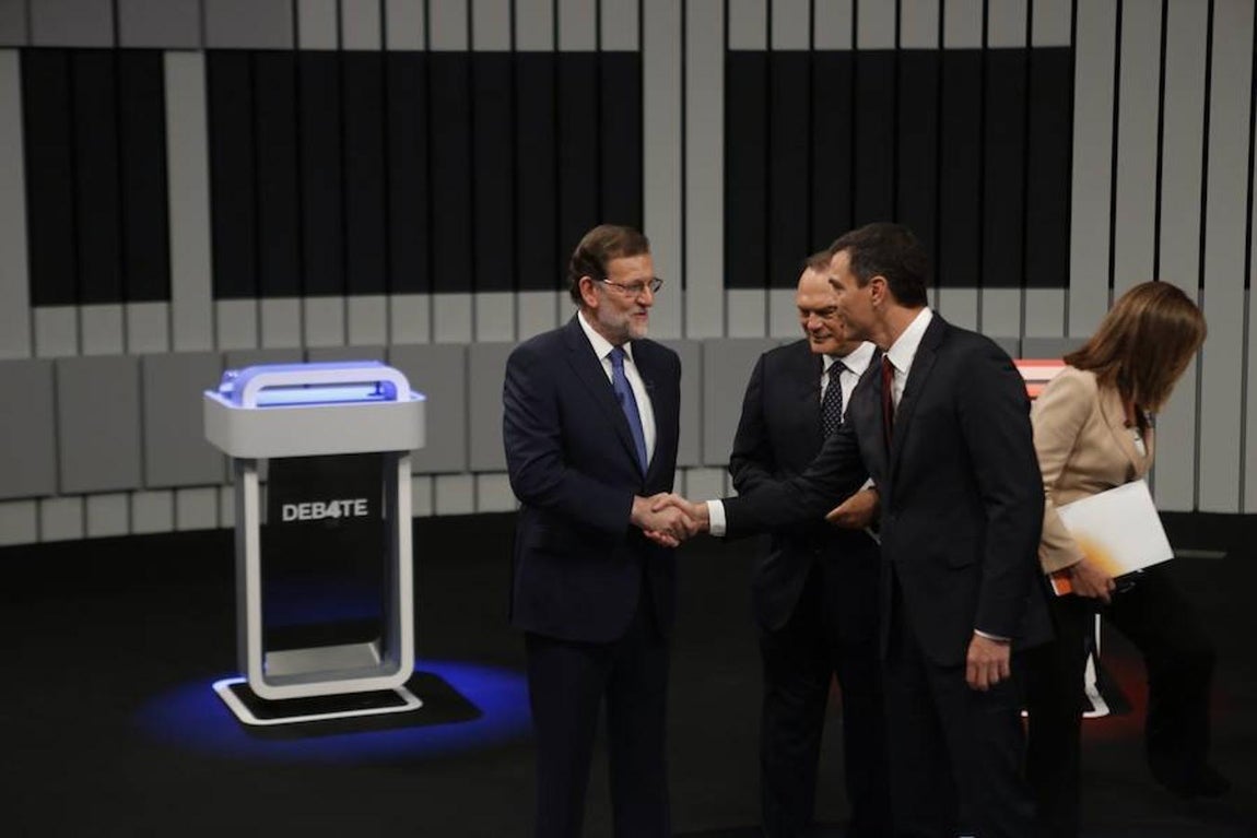 Rajoy y Sánchez se dan la mano antes de ocupar sus respectivos atriles. 
