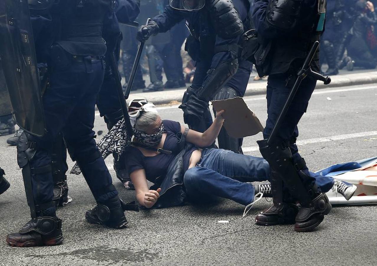 Una mujer cae al suelo en medio de los disturbios. 