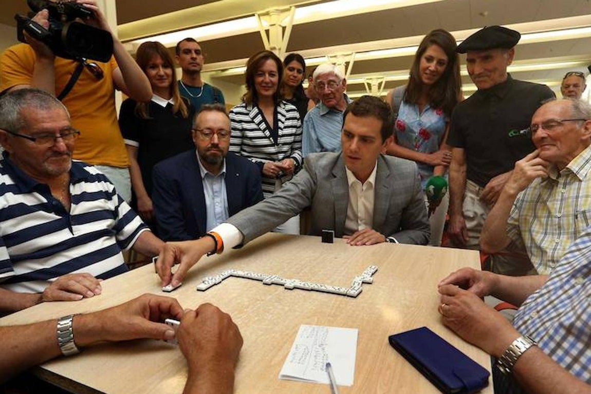 Albert Rivera, acompañado del cabeza de lista por Barcelona, Juan Carlos Girauta, juega una partida de dominó durante su visita al «Casal de Gent» Gran Can Saladrigas en Barcelona. 
