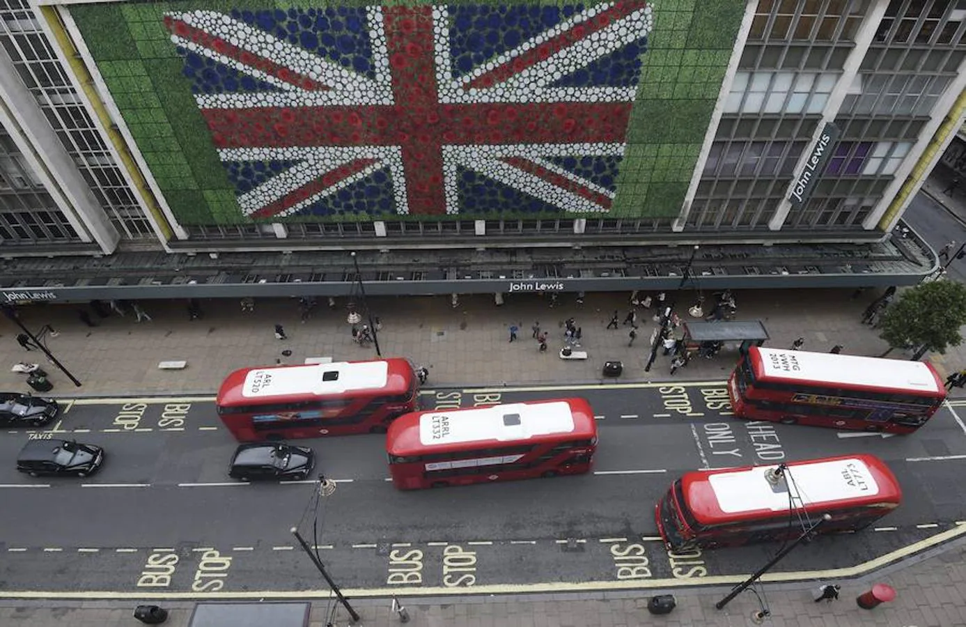 Peatones caminan por Oxford Street, en Londres, donde se ha colocado una bandera británica en la fachada de unos grandes almacenes