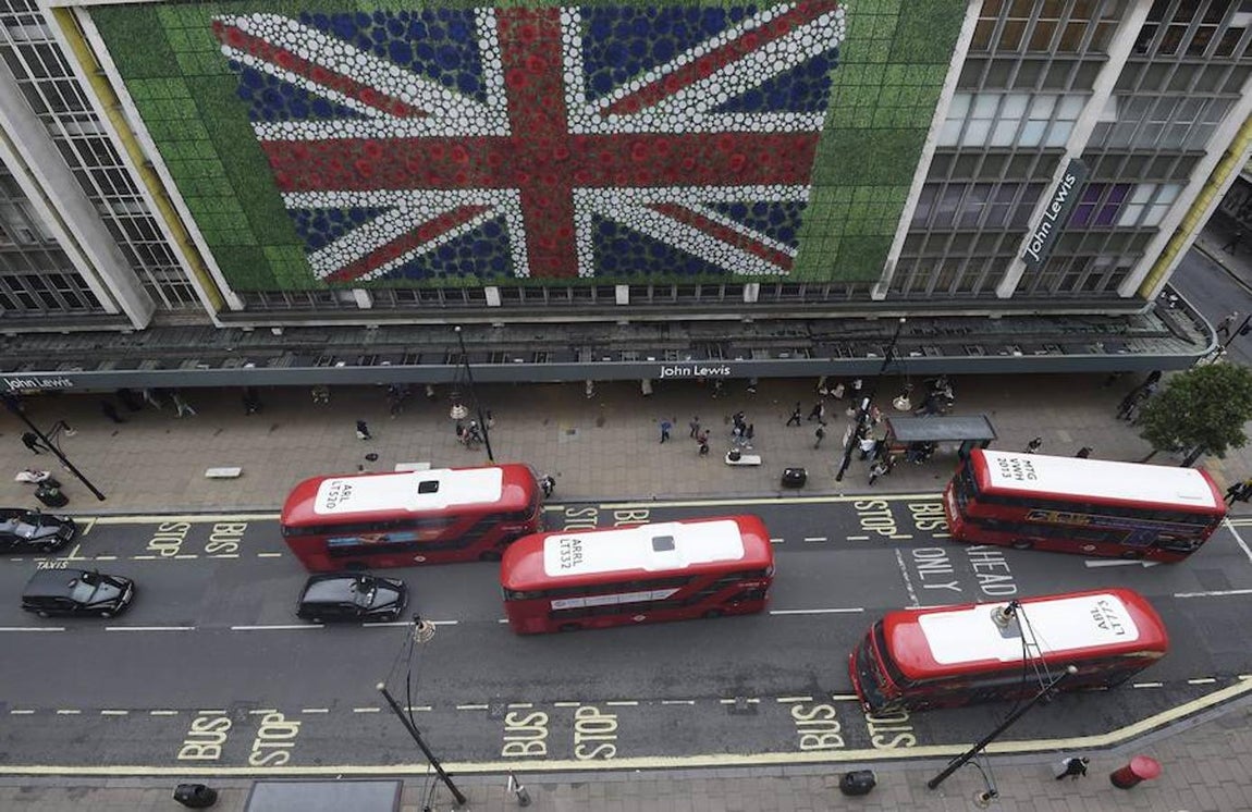 Peatones caminan por Oxford Street, en Londres, donde se ha colocado una bandera británica en la fachada de unos grandes almacenes. 