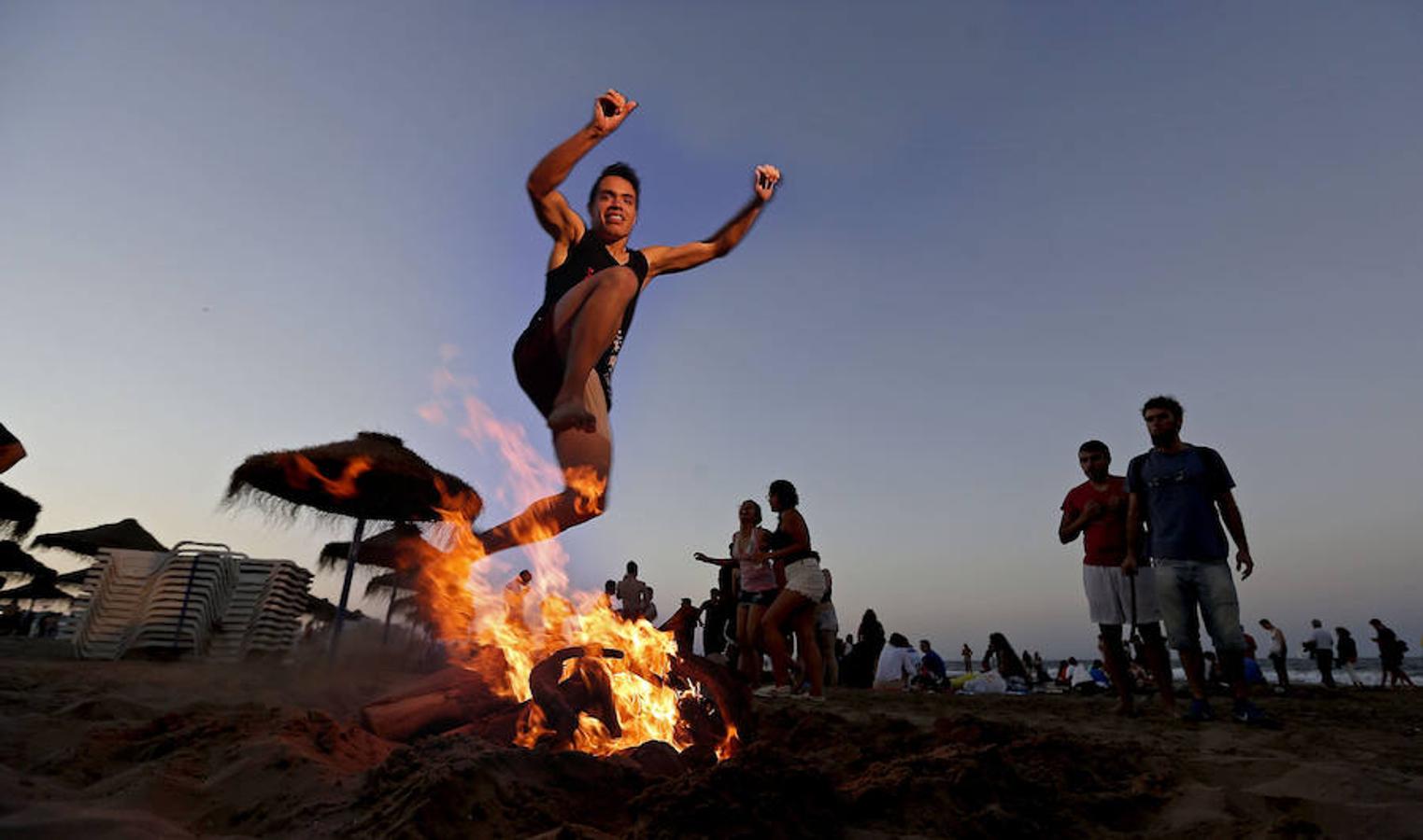 Un joven salta una hoguera, como manda la tradición, esta noche en la playa de la Malvarrosa de Valencia. 