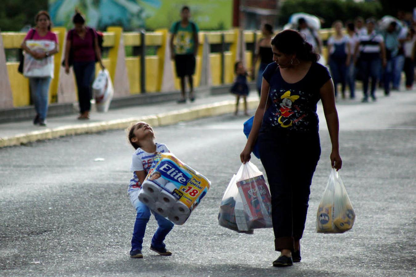 Una niña ayuda a su madre a llevar un paquete de papel higiénico. 