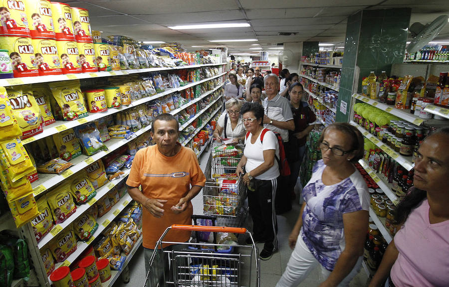Varios venezolanos llenando el carro de la compra en un supermercado colombiano
