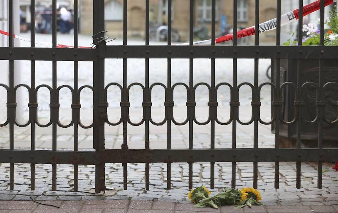 Varios girasoles depositados tras una verja en el lugar del suceso. 