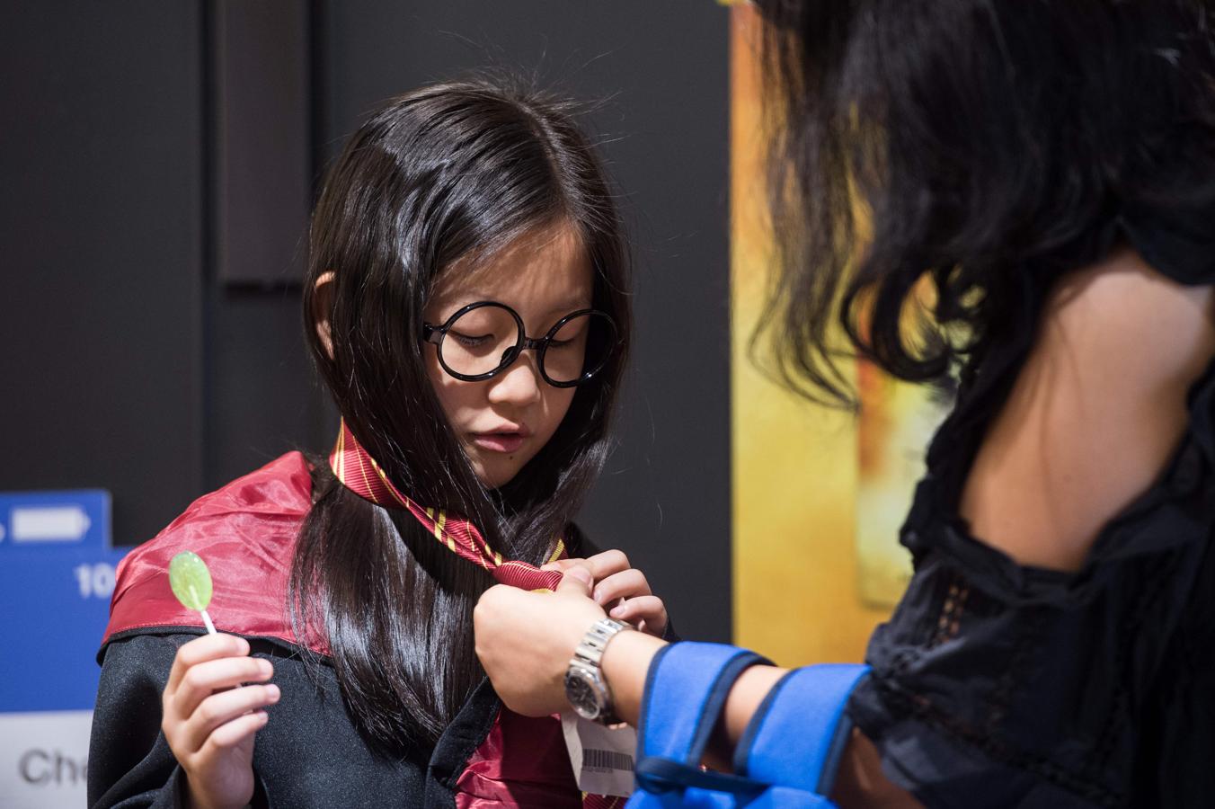 Niña con capa, gafas y corbata de la saga en Hong Kong. 