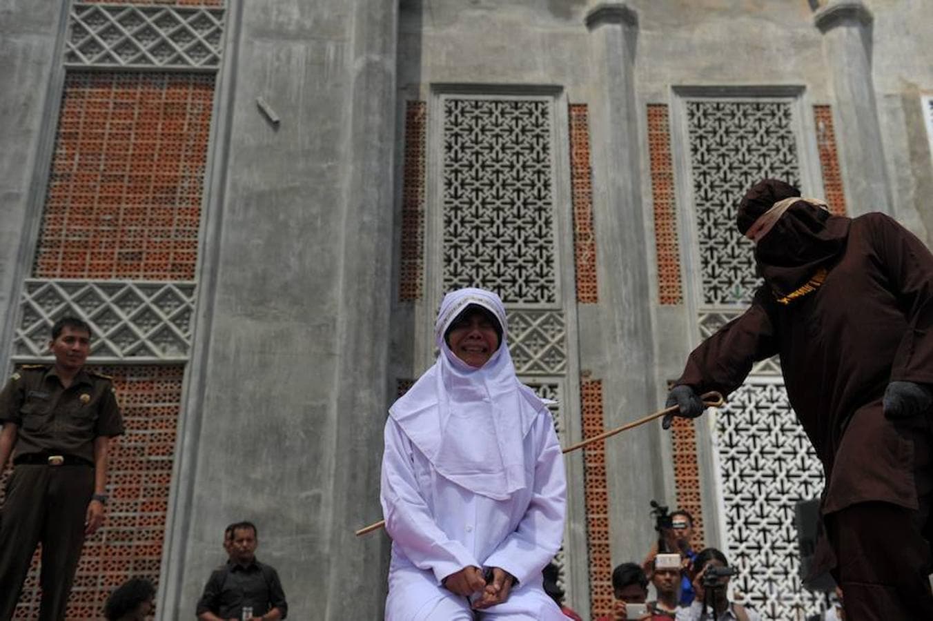 Una de las seis personas que este luner han sido sometidas a la humillación pública en Indonesia llora mientras le azotan