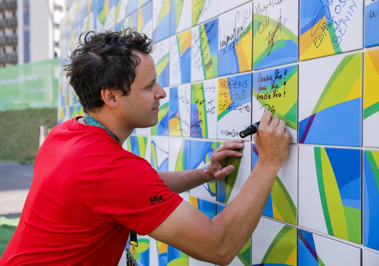 El muro de la Tregua. Un miembro del equipo suizo firma la pared dedicada a reivindicar la paz mundial durante los Juegos Olímpicos