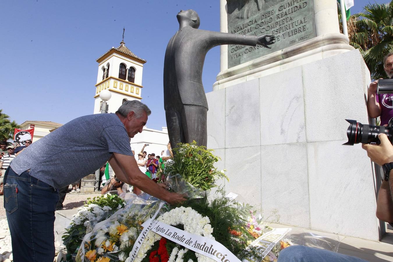 Diego Cañamero entregando un ramo de flores silvestres ante el monolito a Blas Infante