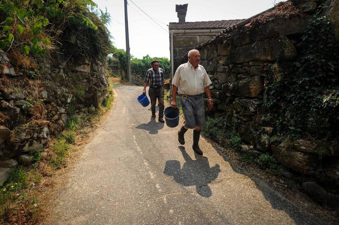 Vecinos de Arbo cargan con cubos de agua para ayudar a los bomberos. 