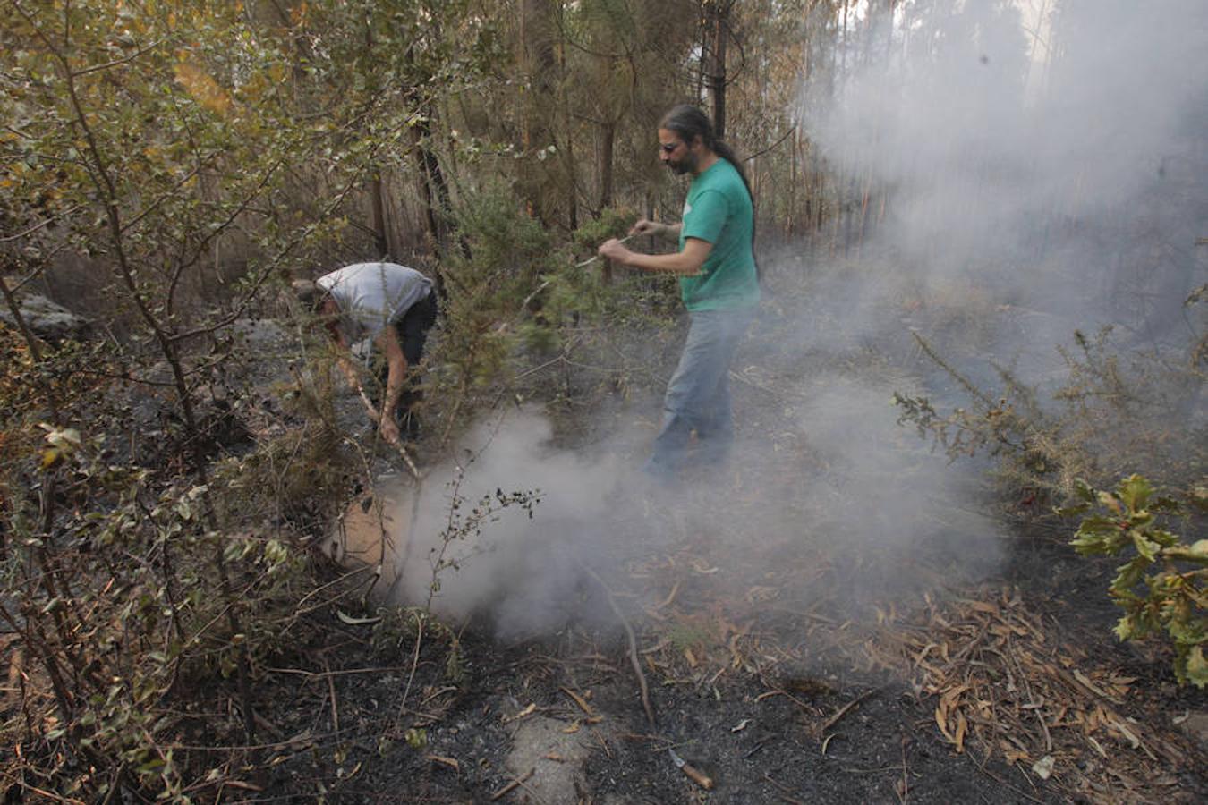 Dos vecinos intentan sofocar un foco del incendio que afecta al municipio coruñés de Porto Do San. 