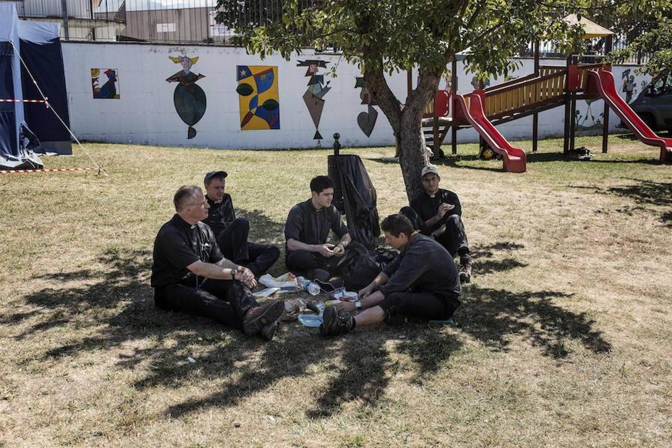 Un grupo de sacerdotes descansa bajo la sombra de un árbol en la localidad Pescara del Tronto 