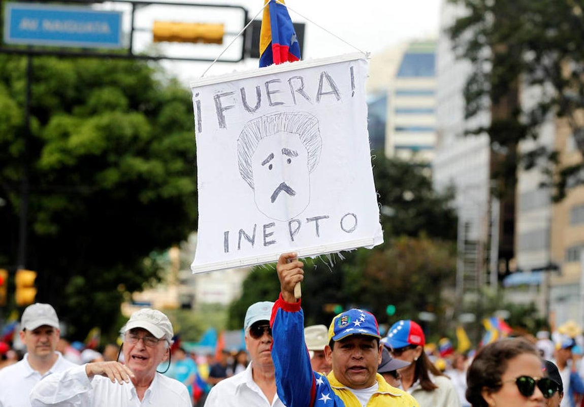 Un venezolano sostiene un cartel con el rostro de Maduro y la palabra «Inepto». 