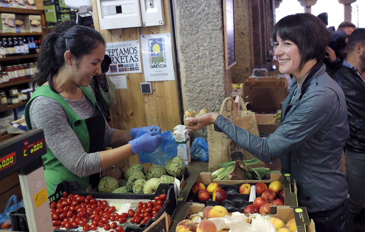 La candidata del BNG a la Presidencia de la Xunta, Ana Pontón (d), compra fruta en el mercado de abastos de Santiago de Compostela durante la jornada de reflexión.