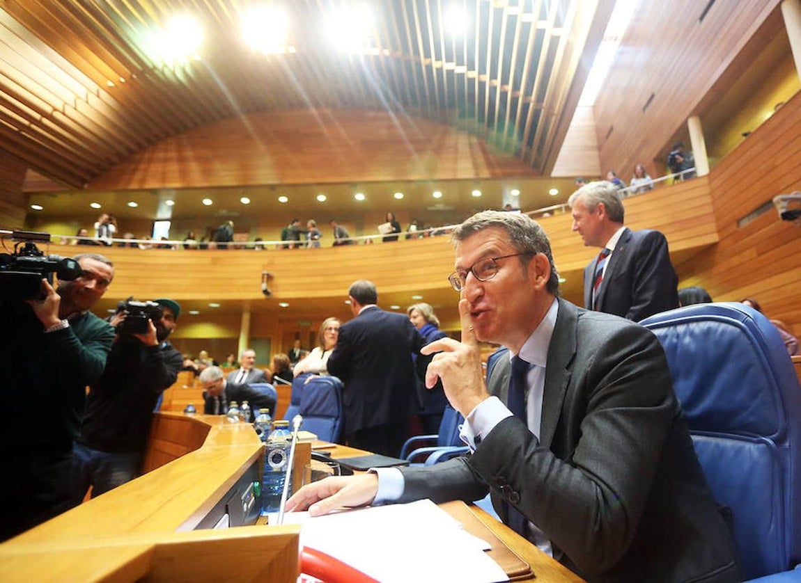 Feijóo bromea con los fotógrafos al sentarse en su escaño. 