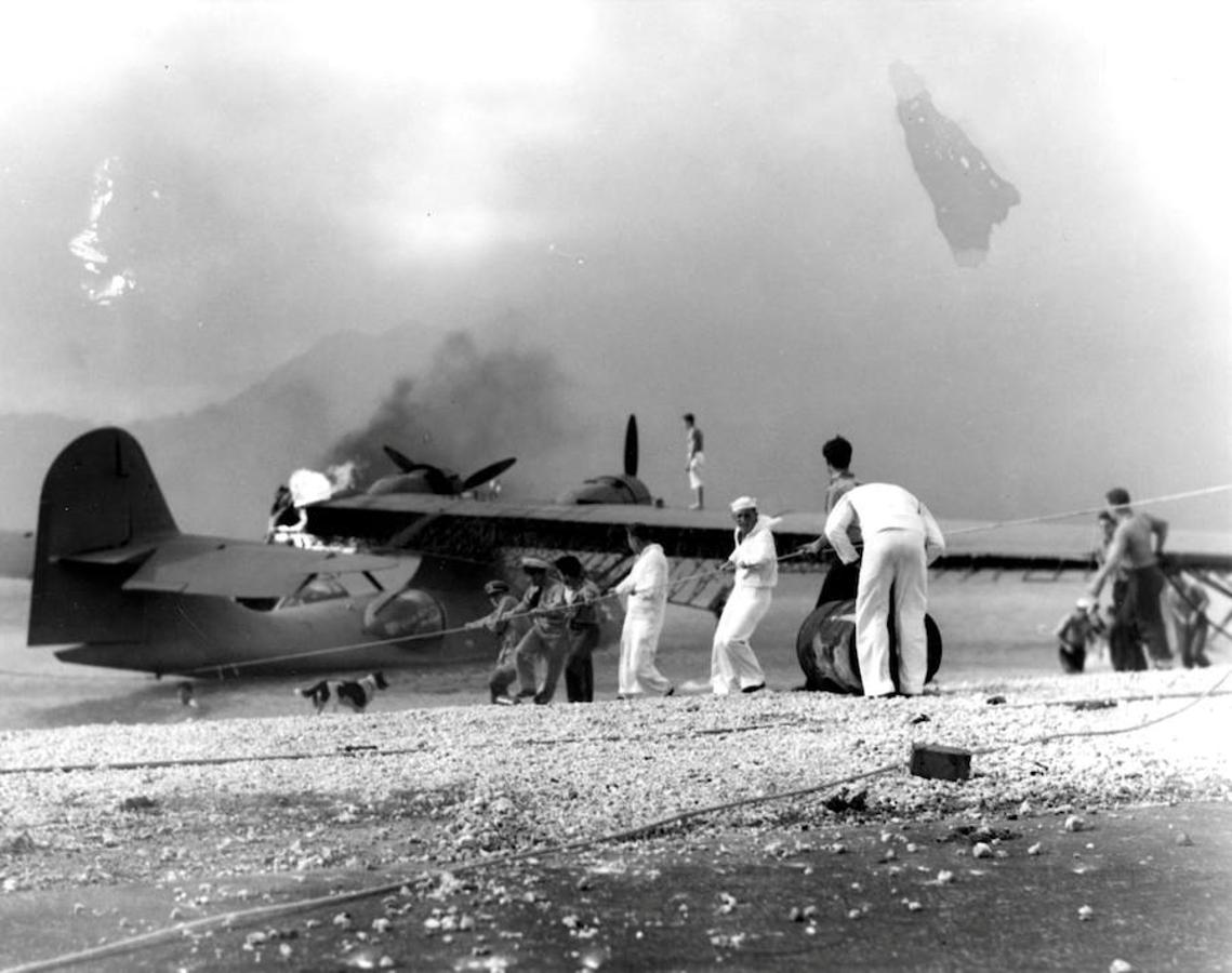 Un grupo de soldados intenta salvar un avión anfibio de las fuerzas armadas de EE.UU. envuelto en llamas tras el ataque. 