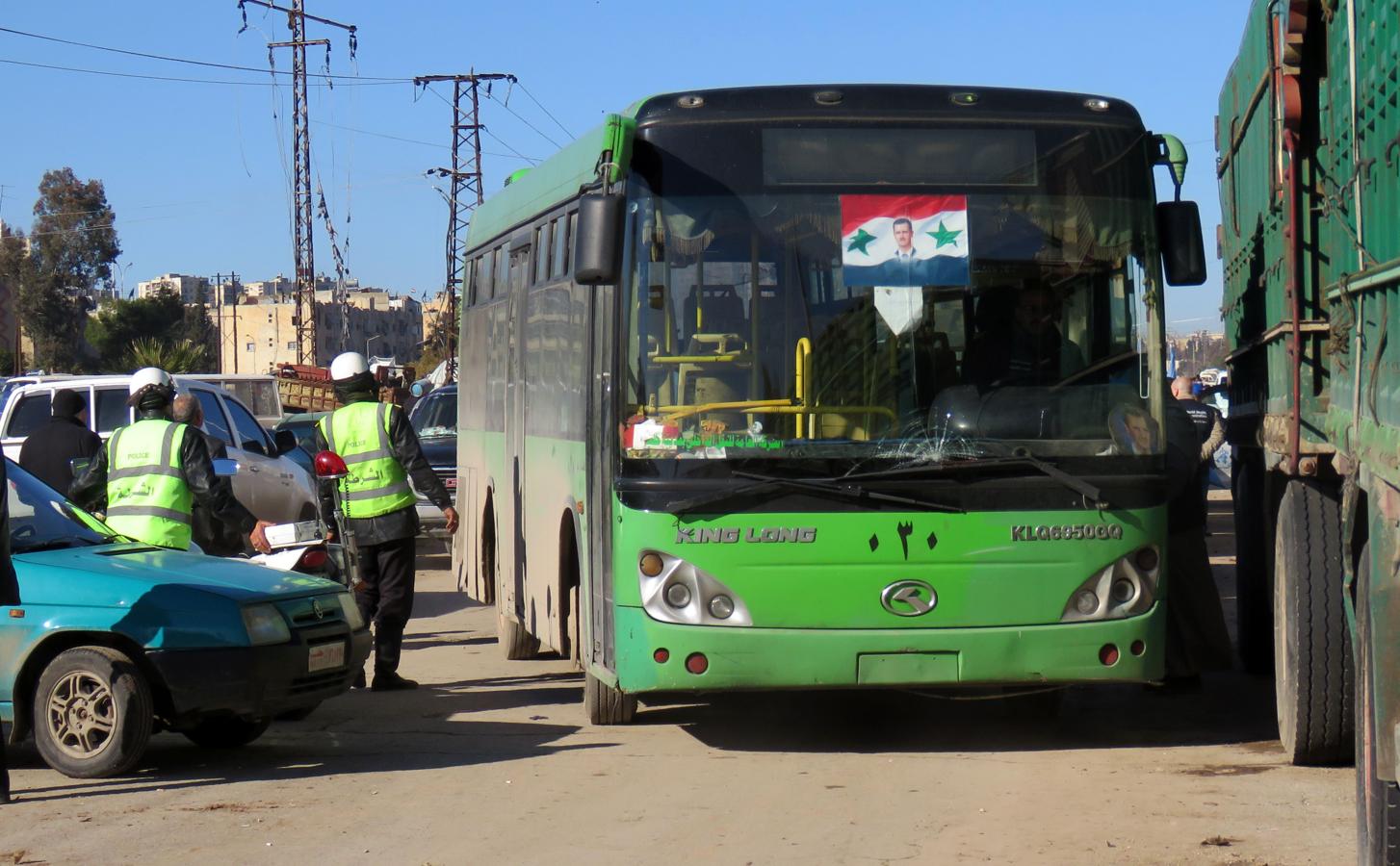 Un autobús para evacuar a habitantes del este de Alepo con la foto de Bashar Al Assad