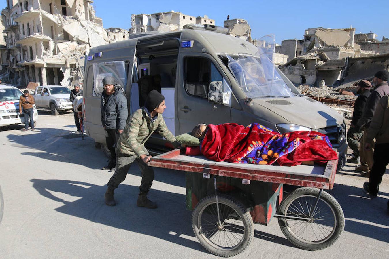 Un hombre empuja el carro en el está tumbada una mujer en plena evacuación de la zona rebelde del este de Alepo.