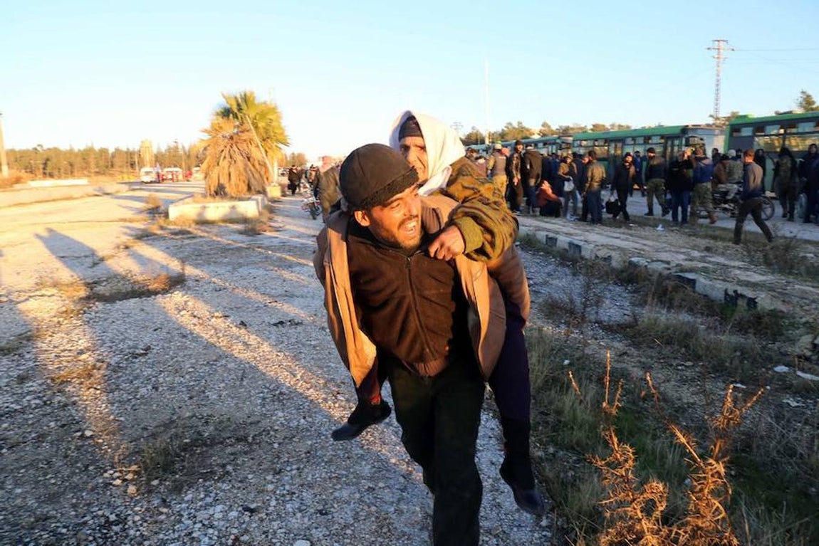Un hombre carga con una anciana a sus espaldas durante la evacuación del este de Alepo.. 