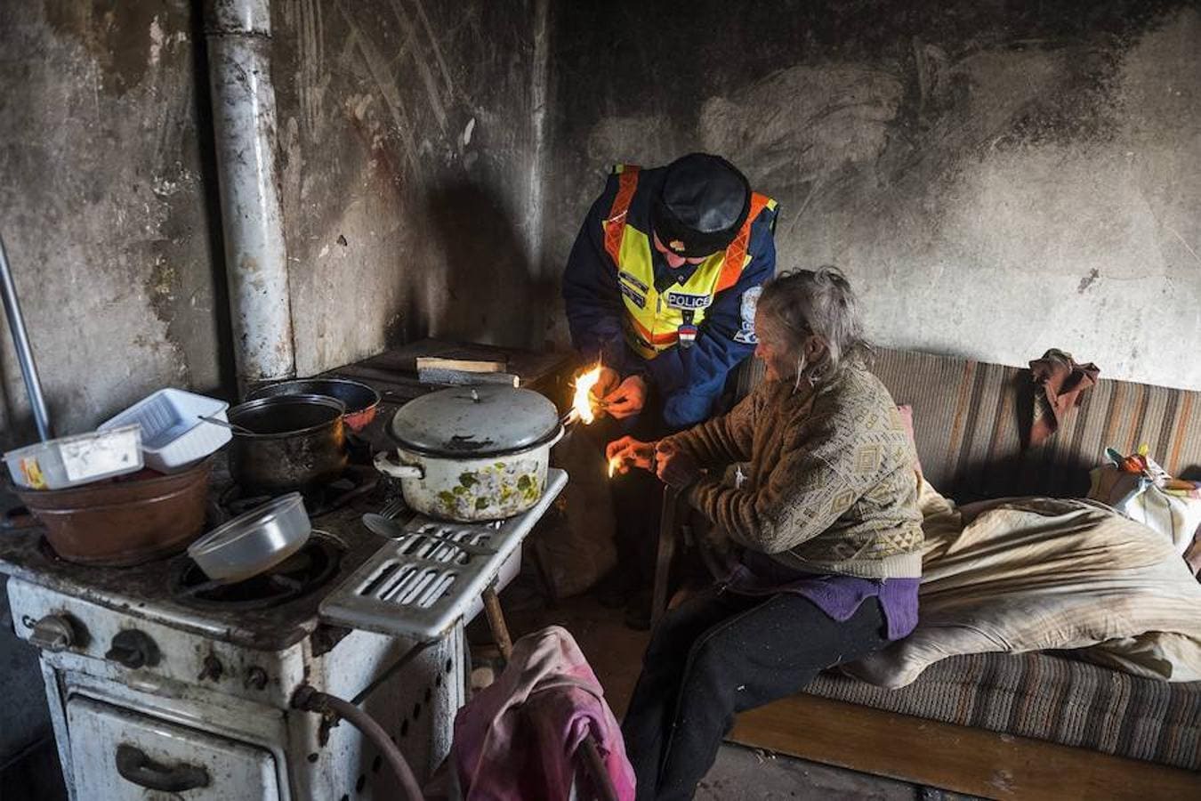 El agente de policía Attila Biszku enciende la estufa en la vivienda de una mujer sin recursos en Nagycserkesz (Hungría)