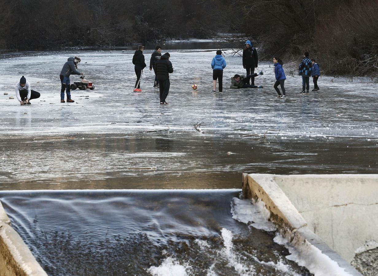 Un grupo de jóvenes juegan con un balón sobre la superficie helada del río Esca, en Burgui, Navarra, cuyo cauce amaneció con una capa de hielo de diez centímetros