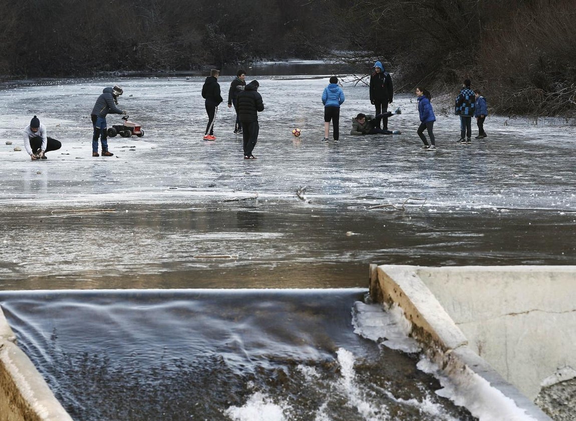 Un grupo de jóvenes juegan con un balón sobre la superficie helada del río Esca, en Burgui, Navarra, cuyo cauce amaneció con una capa de hielo de diez centímetros. 