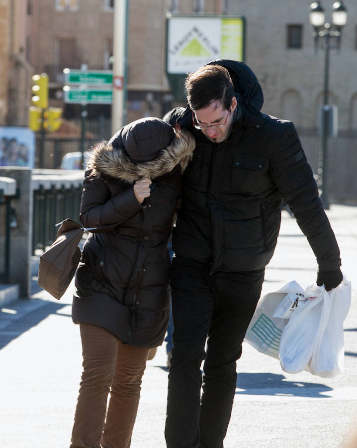 Una pareja de jóvenes sortea el fuerte viento en el Puente de Santiago de Zaragoza. 