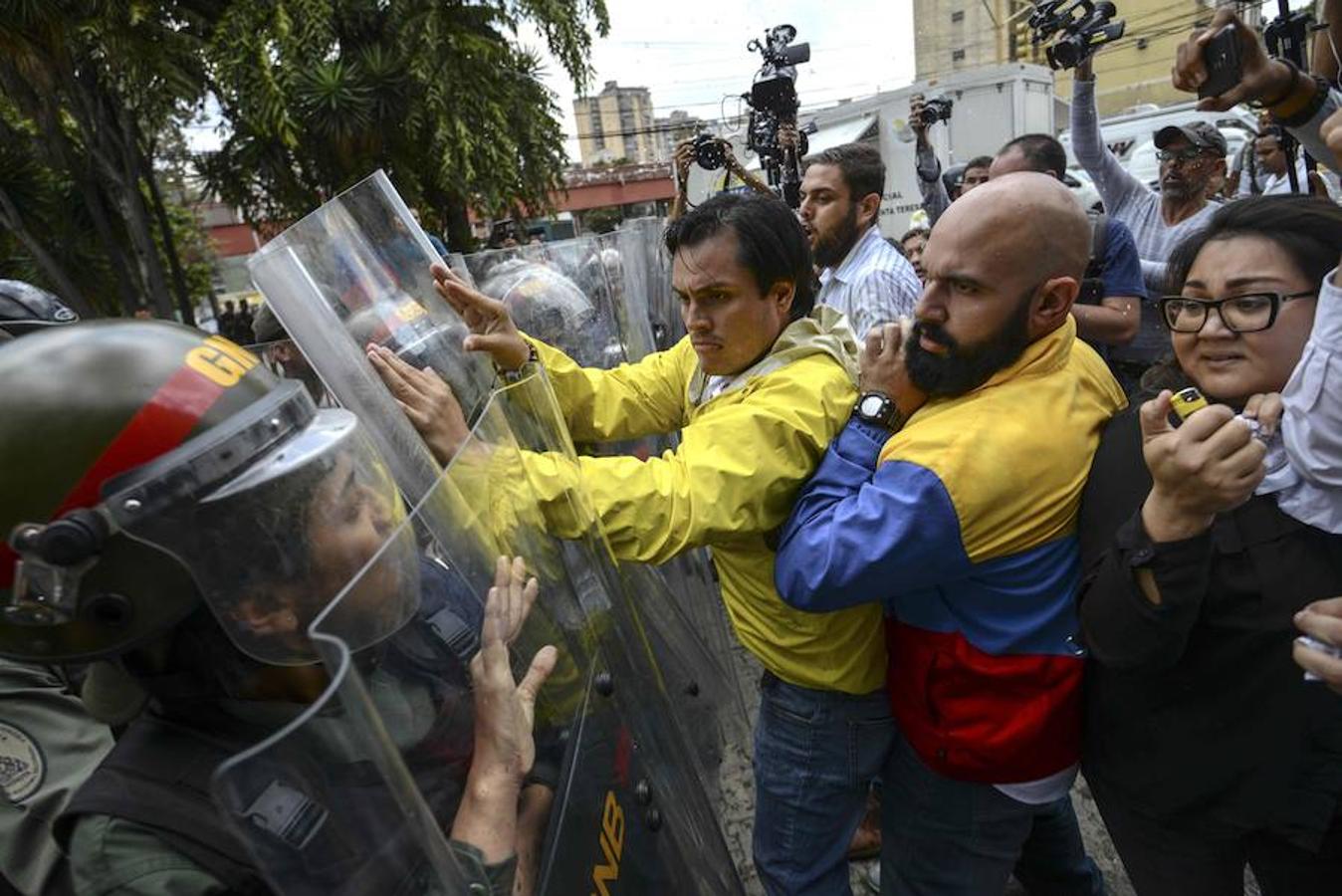 Los diputados de la oposición venezolana Carlos Paparoni y Carlos Bozo empujan los escudos con que se protege la Guardia Nacional en una protesta frente al Tribunal Supremo, en Caracas.. 