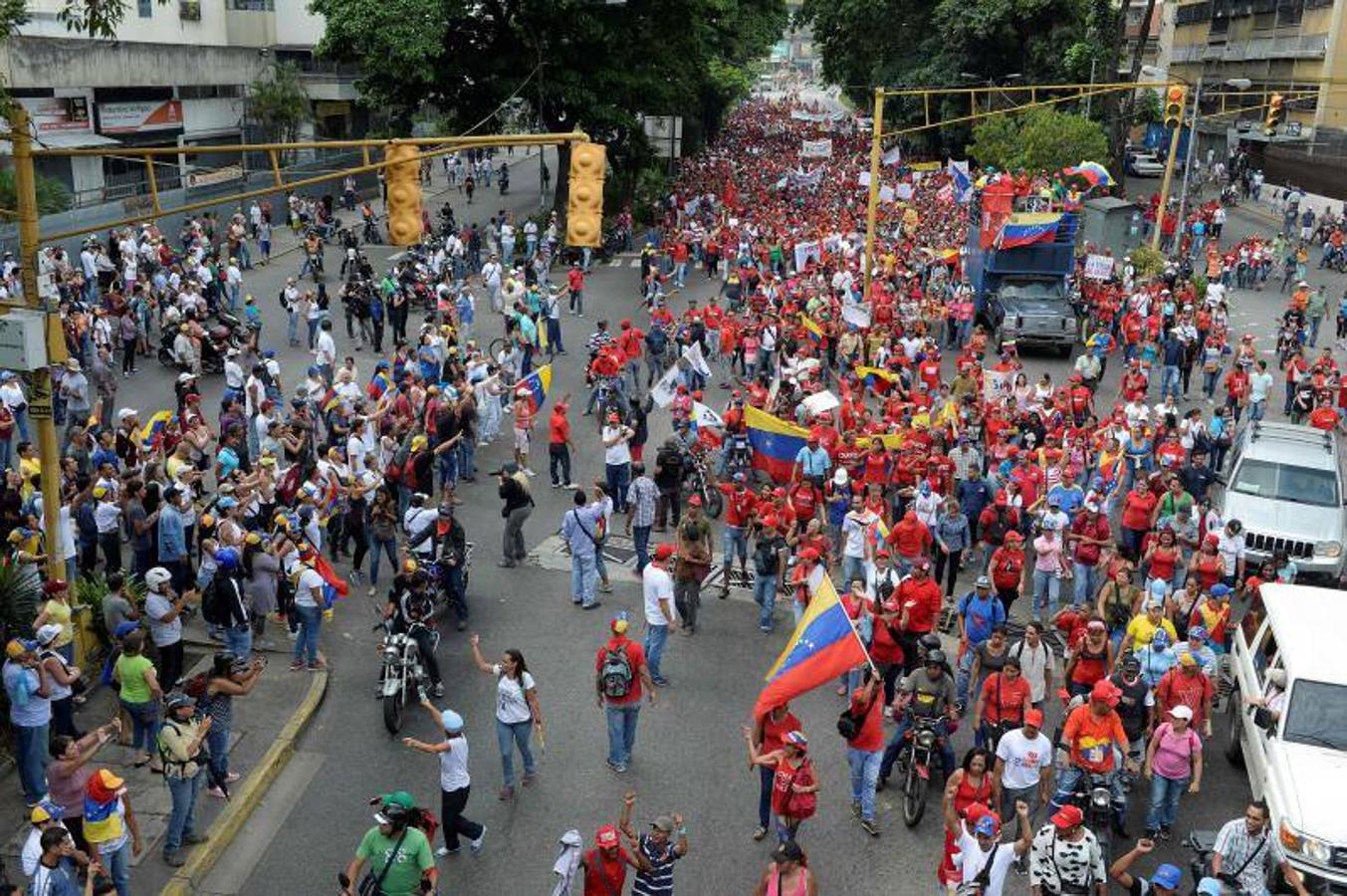 Los manifestantes en apoyo del gobierno del presidente Nicolas Maduro (C en rojo) marchan hacia el centro de Caracas mientras los manifestantes anti gubernamentales (en L) les gritan consignas
