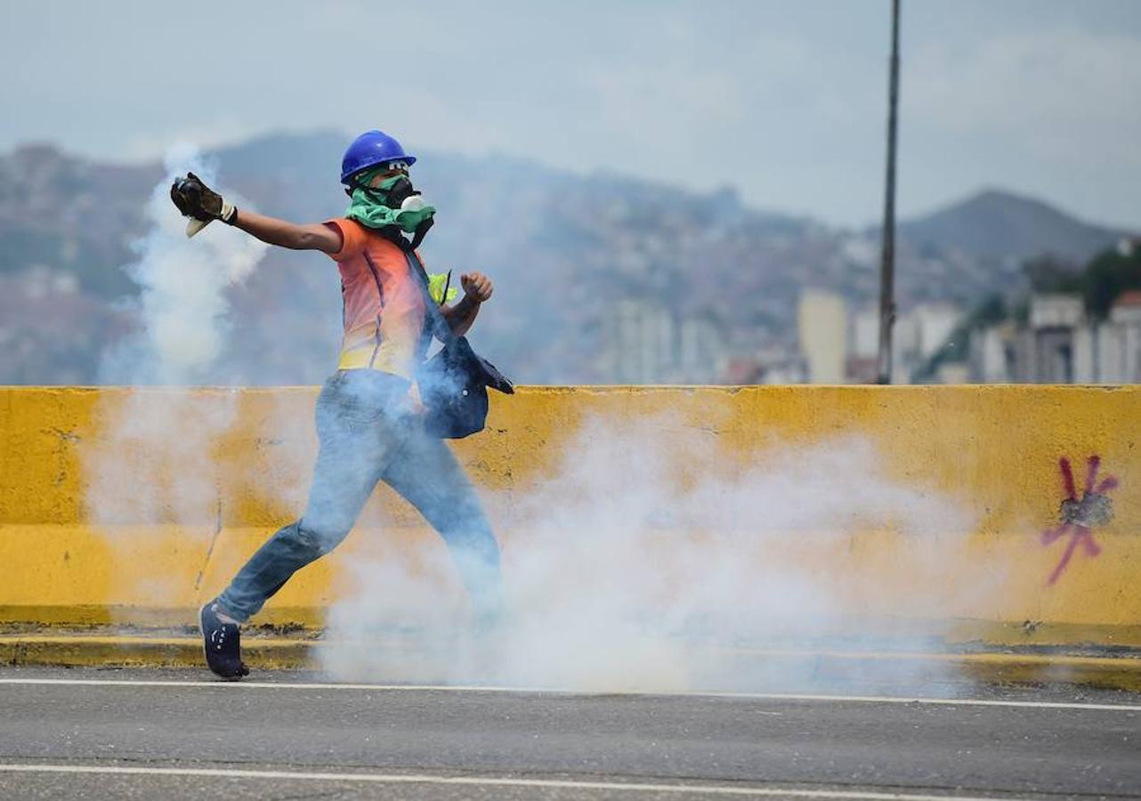 Gas lacrimógeno. Un manifestante arroja gas lacrimógeno a la policía durante enfrentamientos.