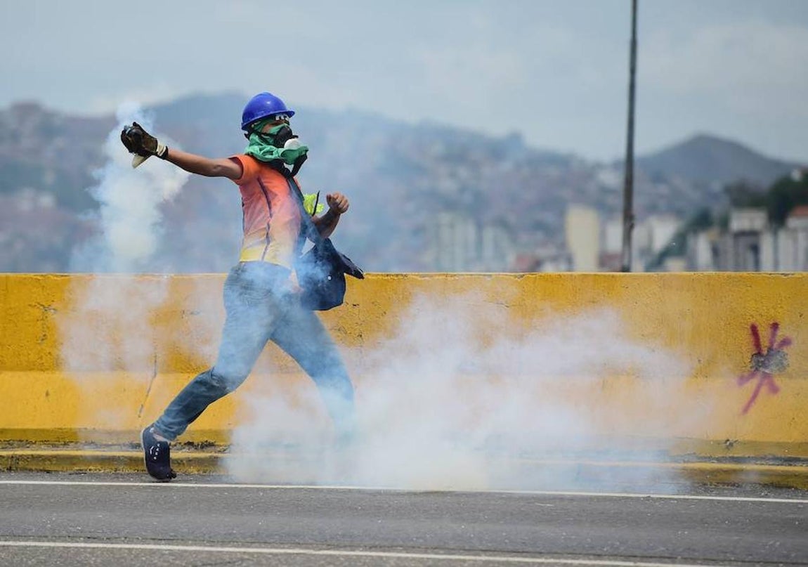Gas lacrimógeno. Un manifestante arroja gas lacrimógeno a la policía durante enfrentamientos.