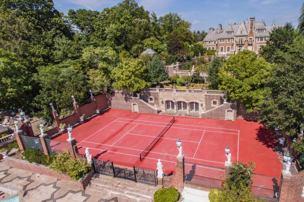 Vista al campo de tenis y al porche de la casa.