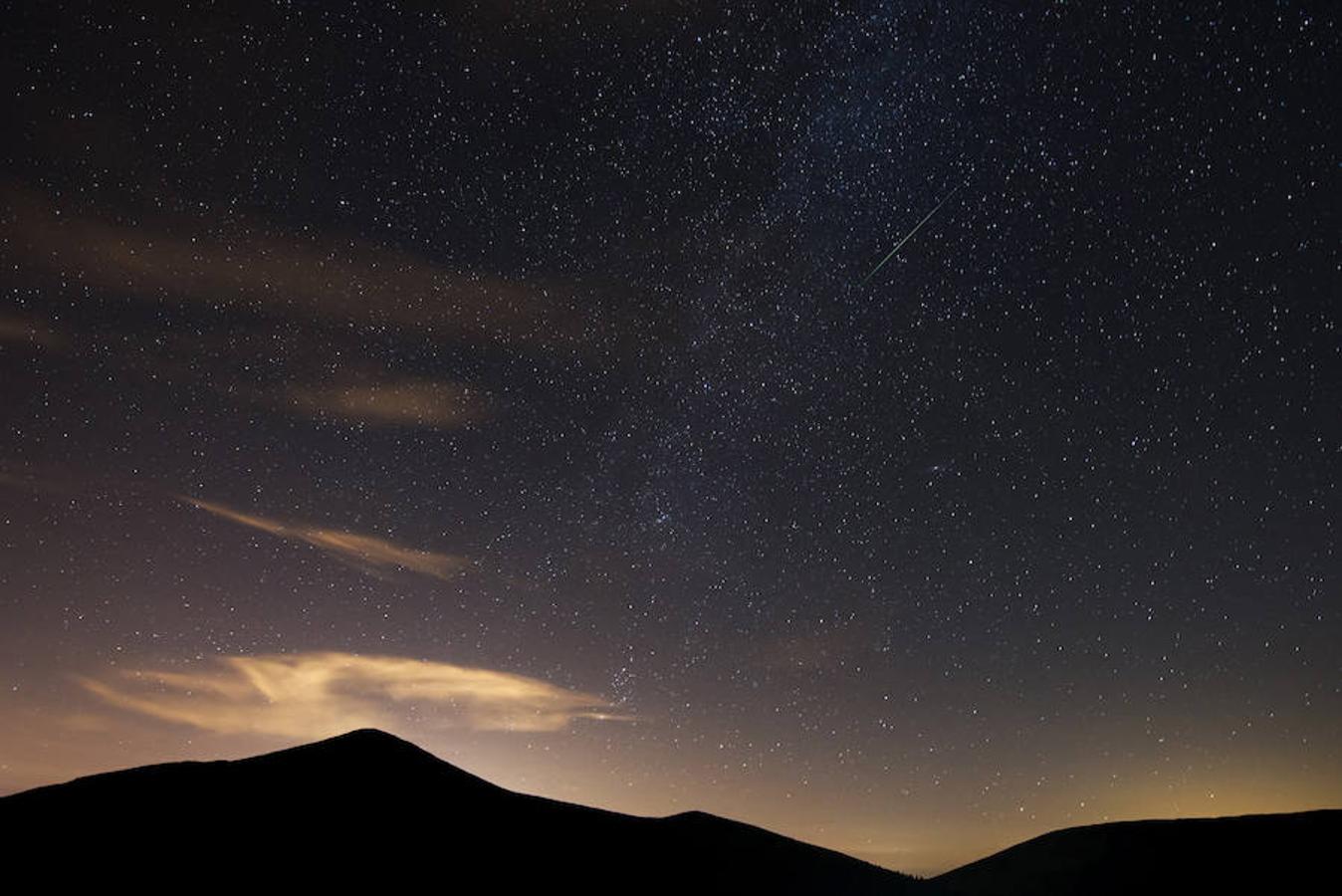 Lágrimas de San Lorenzo. Una perseida atraviesa el cielo junto a la Vía Láctea en Cantabria, una de las noches de máxima actividad de este fenómeno producido al atravesar la tierra la trayectoria del cometa Swift-Tuttle.