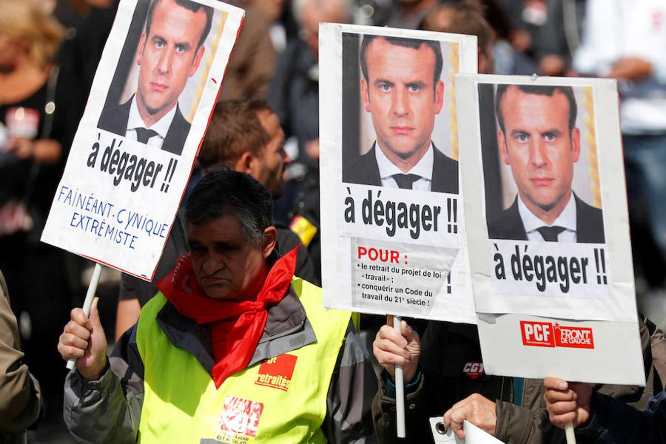 Manifestantes con las fotografías de Macron. 