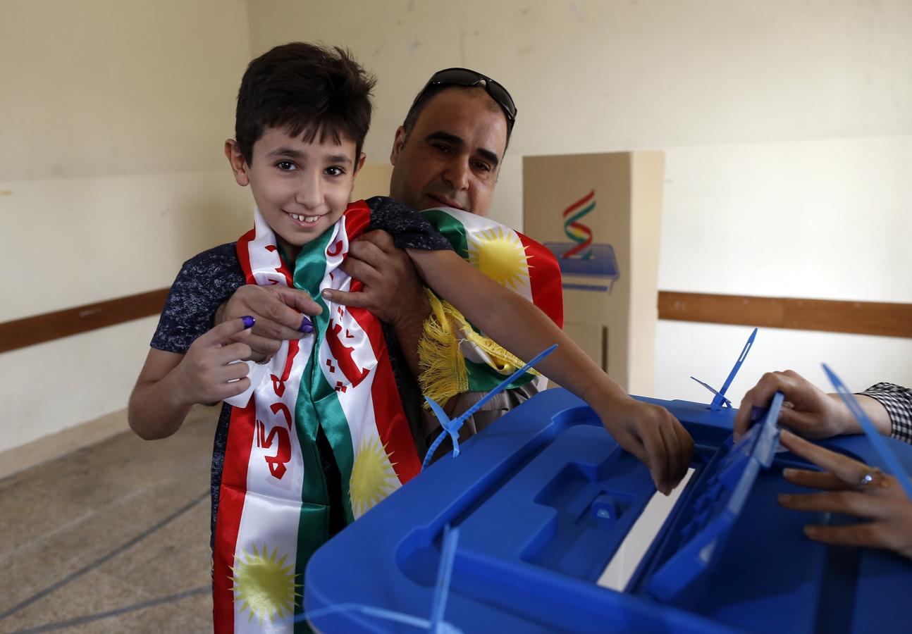 Un niño iraquí coge una papeleta para su padre antes de votar en el referéndum de independencia en un centro electora. 