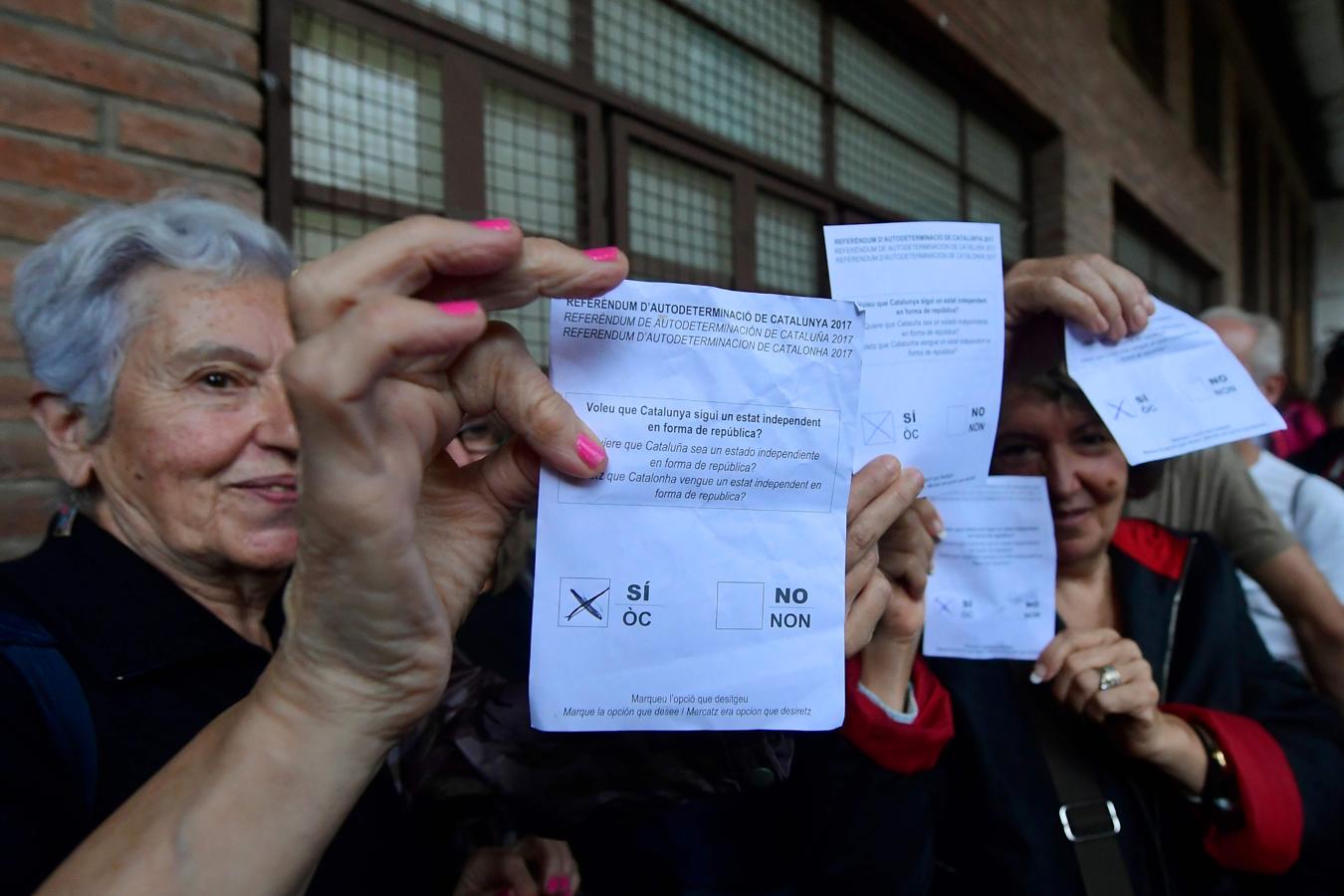 Varios votantes muestras su voto. 