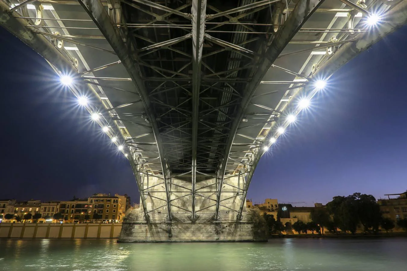 El puente de Triana visto desde abajo se convierte en una gran arcada de luz