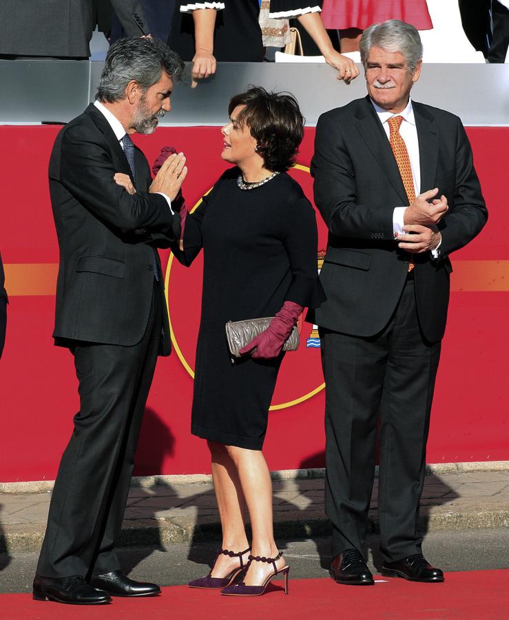 El presidente del Tribunal Supremo y del Consejo General del Poder Judicial, Carlos Lesmes, conversa con la vicepresidenta del Gobierno, Soraya Sáenz de Santamaría, en presencia del ministro de Asuntos Exteriores, Alfonso Dastis, durante el desfile del Día de la Fiesta Nacional (EFE). 