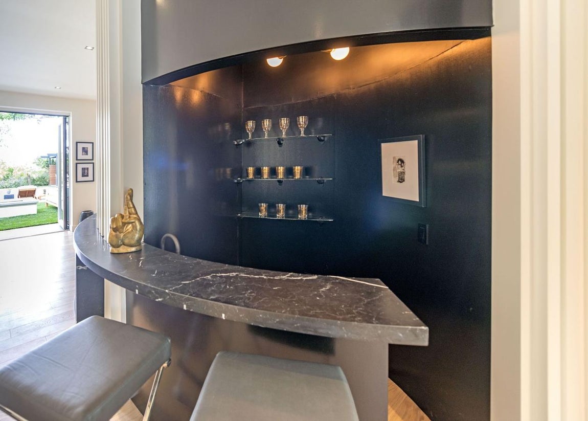 Bar. Toda casa que quiera presumir de exclusiva debe tener un minibar, es un distintivo de la vivienda de lujo. Un lugar para las reuniones y el ambiente distendido. La barra de mármol de carrara es muy elegante, es curva y de color negro