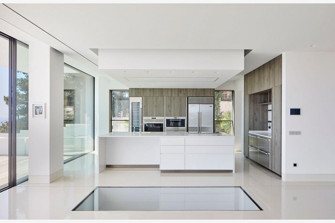 Planta baja. En la planta baja se encuentran el salón y la cocina, que son los principales espacios de estar y de reunión. Se proyectaron en esa planta para conseguir una temperatura más agradable. En el primer piso están los dormitorios, en el sótano los garajes, la piscina y un pequeño spa. La azotea, sin embargo, está reservada para la evasión, es todo terraza para proporcionar una experiencia más íntima