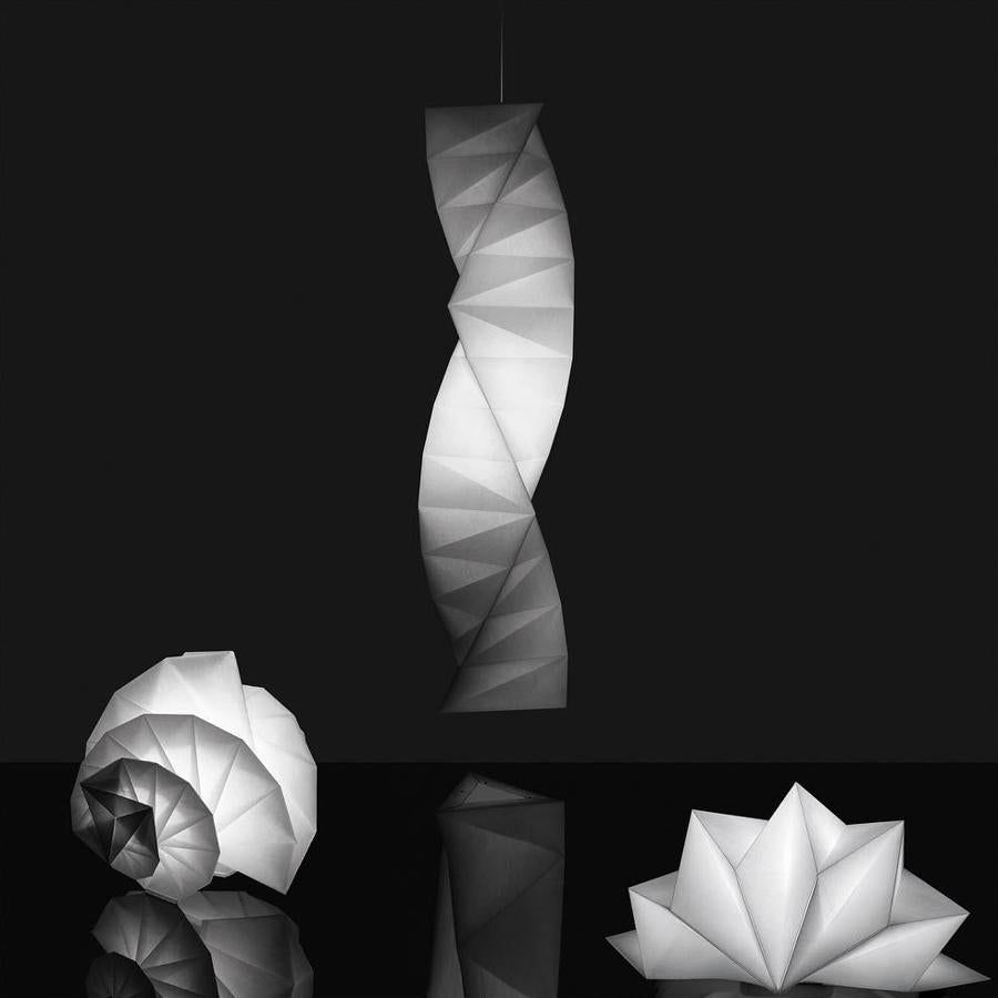 In-EI Issey Miyake. «IN-EI» en japonés quiere decir «sombra, oscuridad, matiz». Iluminación, creatividad y matemáticas se funden en este proyecto, que consiste en crear un efecto escultórico de luces y sombras aplicando la ciencia a la doblez de la tela, que adquiere formas tridimensionales a partir de un solo corte.El arte de iluminar debe parte de su herencia conceptual y tecnológica al Miyake Design Studio y a los principios de la tecnología 3D de Juan Mitani