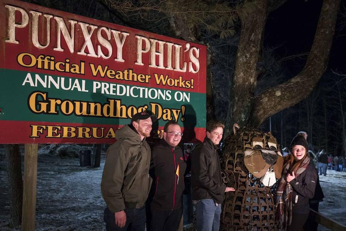 Varios espectadores posan junto a una estatua de la marmota.. 