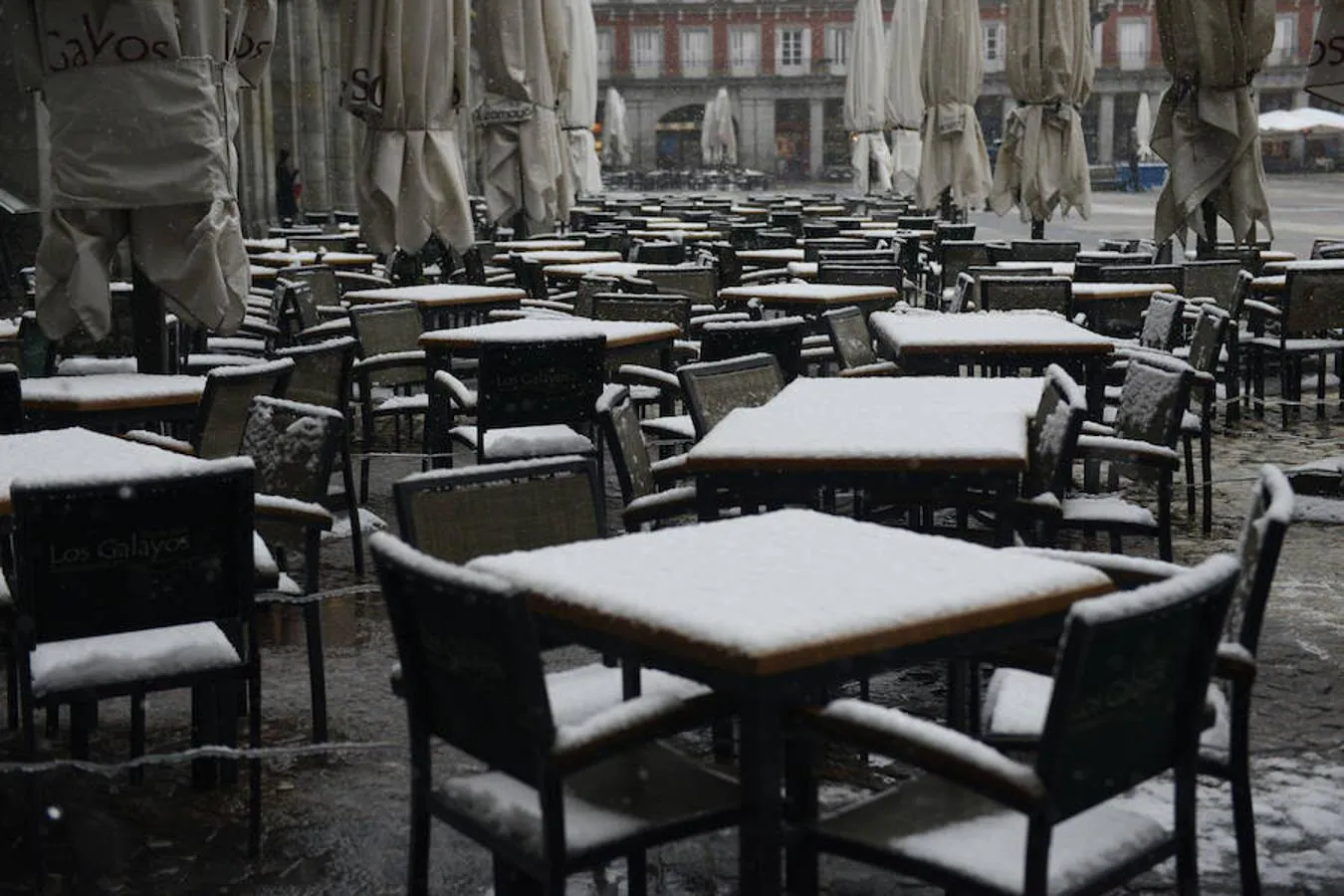 Mesas y sillas de las terrazas de la Plaza Mayor de Madrid, cubiertas de nieve.. 