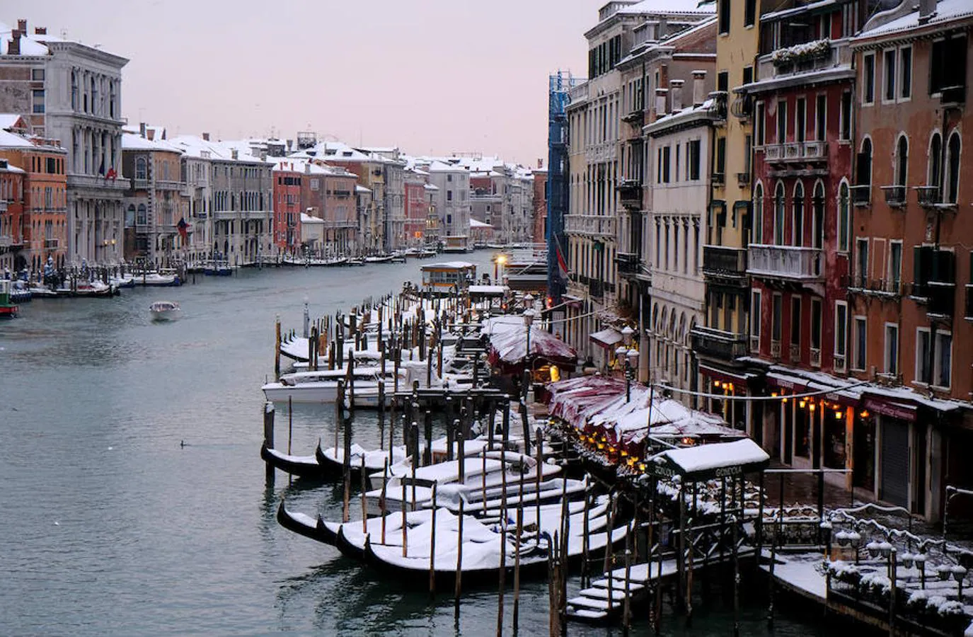 Góndolas aparcadas y cubiertas de nieve en el Gran Canal de Venecia.. 