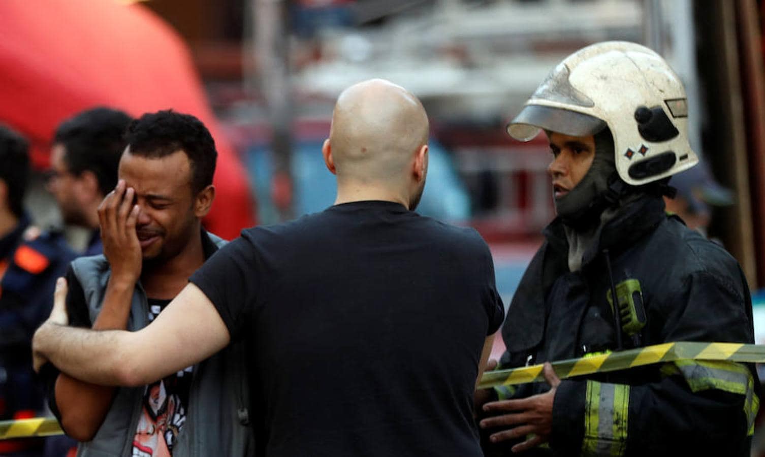 Oficiales de bomberos atienden a un hombre cerca del lugar donde se derrumbó un edificio en el centro de Sao Paulo. 