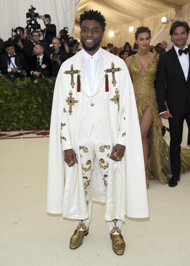 Chadwick Boseman. El blanco fue uno de los colores más escogidos en la gran noche del MET 2018. El actor apareció con un esmoquin con chaleco en color blanco con motivos dorados y una capa con cruces de inspiración religiosa de Versace; que combinó con mocasines dorados de Christian Louboutin.