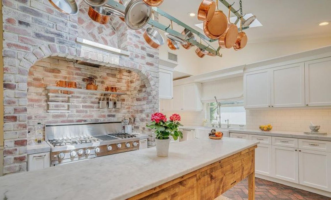 Cocina «gourmet». En la cocina la pared está adornada con ladrillo. Tiene una enorme barra de desayuno con espacio para almacenaje en madera y electrodomésticos de alta gama